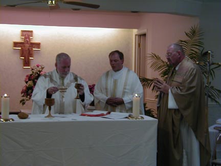 Image of Fr. Kenn standing at the altar with two bishops who ordained him.